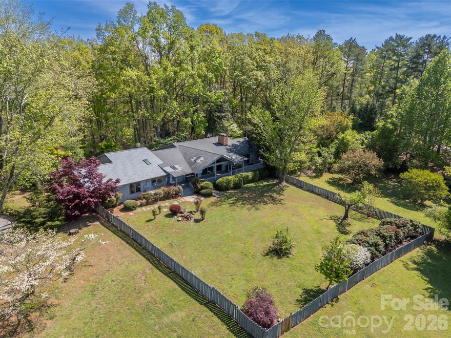 Tucked along a private drive in the sought-after Hunting Wood community, this Tryon retreat on 9.6 acres offers the rare combination of extensive, one-level living space, privacy, and “lifestyle” amenities. The main residence features 3,125 heated sq ft with 8 natural light-filled rooms, 4 bedrooms, and 3.5 baths, plus a 603 sq ft finished basement. Enjoy cozy evenings by the fireplace, then step outside to a property designed for everyday living and effortless entertaining. The grounds are a woodland retreat: brick walkways, a vine-draped arbor, wooded garden paths, and a tranquil water garden/pond create a peaceful, storybook setting. Out back, there's a large covered porch with a hot tub and a fenced yard for the dogs. Summer becomes a staycation with the in-ground swimming pool and expansive pool deck—perfect for gatherings, lounging, and outdoor dining. For hobbyists and creatives, the property shines with a detached garage with separate dedicated wood shop, a small greenhouse, and an additional artist studio—a true compound for work, play, and inspiration.
Move-in with confidence: the sellers completed a pre-inspection and proactively addressed the maintenance items identified—delivering a home that feels cared for from top to bottom. In addition to a list of minor items addressed, major improvements include a new roof and crawl space encapsulation. If you’re looking for a home that offers privacy, character, and resort-style amenities—plus the peace of mind of thorough proactive maintenance—this is a must-see.