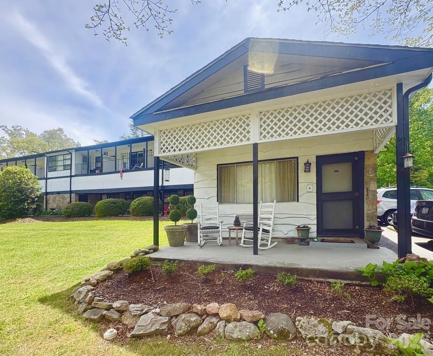 Welcome to a rare find in the heart of historic Flat Rock — a freestanding studio condo with lake views, nestled within Mill House Lodge. This small mountain community is centered around the historic Millhouse, complete with a waterfall and stream. Step out from your private entrance and patio to enjoy the private lake, paddle sports, a fire pit, an outdoor pool, tennis courts, and a lakeside deck. Inside, you'll find charming stone walls, custom drapery, and low-maintenance flooring. All utilities including electric, water, sewer, cable, wifi, and trash pickup are covered by the monthly HOA, with shared laundry on-site. Short-term rentals are permitted and have a strong track record here, making this an appealing option whether you're seeking a full-time residence or an income-producing investment. Seller is open to including furnishings with an acceptable offer. Located just 10 minutes from downtown Hendersonville and moments from the Carl Sandburg Home and Flat Rock Playhouse. Come visit Rhodes Cottage today!