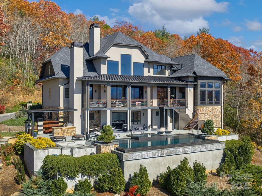 Extravagant, private 24-acre Fairview estate where industrial-chic meets elevated resort-style living. Over 10,000 SF of sleek contemporary architecture, award-winning spaces, and world-class amenities once dubbed “The Oasis with Everything” by Carolina Home & Garden. 
The main level is clean and modern: soaring 25’ ceilings, porcelain tile fireplace wall, exposed steel beams, rift & quartered European white oak flooring, high-end custom stone details, and a showstopper Brazilian quartzite island kitchen and turquoise stove with brass range hood. Bedrooms are crisp, contemporary, and frame the mountain views beautifully. 
The lower level transforms into an entirely different world with a posh private club environment featuring a full bar, state-of-the art theater, game room, spa/steam room, lounge zones, and private gym. The home’s indoor/outdoor living is anchored by a dramatic infinity pool, upper terrace with motorized phantom screens, and multiple fieldstone outdoor fireplaces.
This property lives like a private luxury retreat — highly private, all the amenities you could ever need, intentionally self-contained, and purpose-built for both solitude and five-star entertaining.