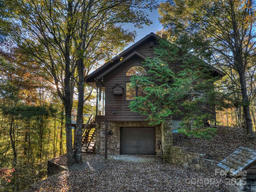 Tucked away in the trees, this custom home rests on 17.4 private acres with sweeping views that stretch from Queens Lake, across the Nantahala Gorge, and over the Lake Fontana basin. Designed and built under the guidance of renowned builder Bill Baxter, every detail reflects a thoughtful balance of comfort and design. Living here feels like being in the treetops, with glass along one wall and strategically placed windows that invite both light and mountain vistas. The open floor plan flows seamlessly from the main living space to the bedroom and office, anchored by a striking stone hearth with fireplace and wood stove.The master bath features a private sauna, and throughout the home you’ll find custom stonework adding texture and character. Outdoor living is equally inviting, with a koi pond, stone terraced garden areas, and a deck inset designed for a wood-fired hot tub. Practical amenities include a ground-floor garage with an electric dumbwaiter for firewood, hydronic floor heating on the main level, and subtle access to a rooftop seating area with even broader views. Enjoy end-of-the-road privacy, direct proximity to Nantahala National Forest, and unlimited natural beauty.