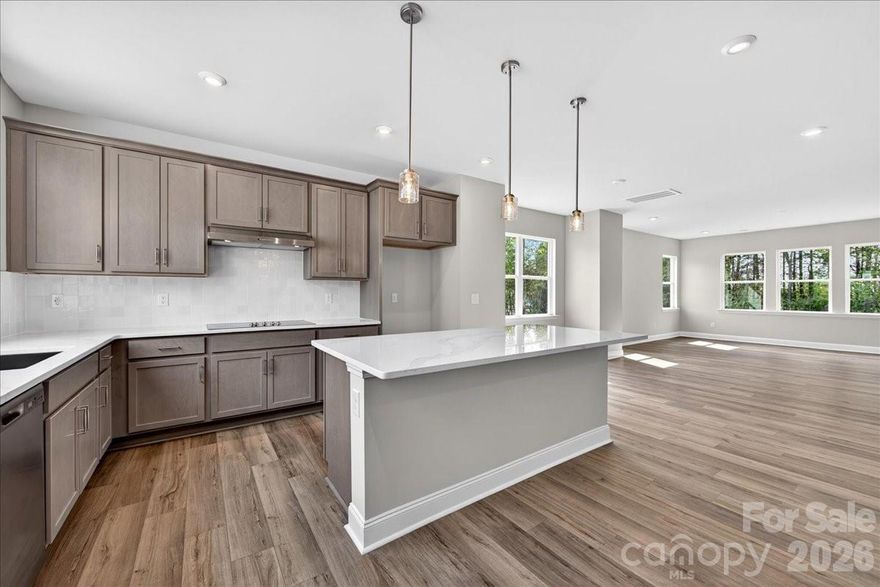 Just released in our sought-after model row, this stunning end-unit townhome offers elevated design, natural light, and flexible living at every turn. From the moment you arrive, you’re welcomed by charming curb appeal and soaring ceilings that create an open, airy feel throughout. The entry level features a convenient drop zone off the garage and a private guest suite with a full bath and tiled shower—perfect for visitors or a home office. Step outside to a serene back patio overlooking wooded views. At the heart of the home, the gourmet kitchen shines with crisp gray cabinetry, quartz countertops, and an oversized window that fills the space with natural light. It flows seamlessly into the open-concept great room, complete with a cozy electric fireplace and access to a second-level outdoor living area. Upstairs, unwind in the expansive primary suite featuring a spa-like bath with sleek white cabinetry and floor-to-ceiling tile—blending timeless design with low-maintenance living.