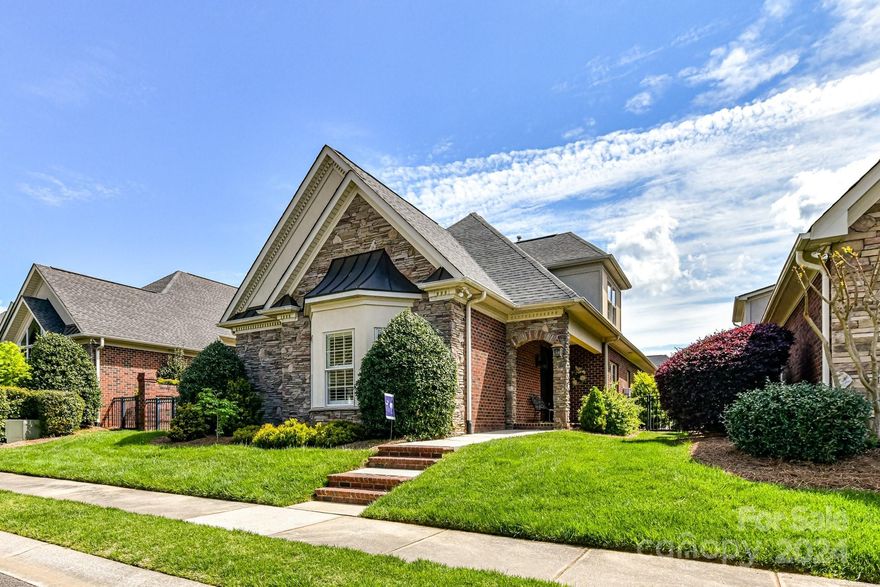 Captivating 1.5 story brick residence featuring Rocking chair porch, luxury vinyl plank flooring, tile, intricate moldings, custom built-ins, and a stylish bar with a wine refrigerator. The grand two-story great room boasts a fireplace, while the formal dining room and breakfast area with a built-in china cabinet offer elegant spaces for dining. The gourmet kitchen is equipped with a center island, gas cooktop, oven, microwave, and granite countertops. The main level hosts a luxurious primary bedroom suite and an office/study. Step outside into your private courtyard, offering a serene retreat for quiet moments alone or an ideal space for entertaining guests. Don't miss the HUGE walk-in attic that could possibly be additional sqft footage if finished. Also hidden storage as well.  Additionally, the home is roughed in for a central vacuum system, and there are locker/cubbies at the rear entry for added convenience.