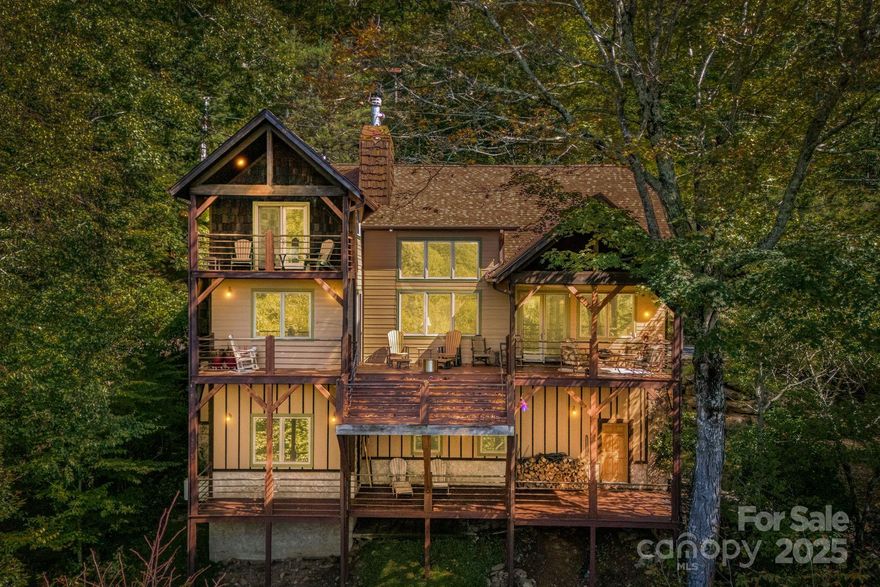 Perched @ 4,100 feet inside Wolf Laurel’s 5,300-acre gated community, 191 Ivy Way delivers what buyers rarely find together, year-round, long-range mountain views from your home, plus a lacework of small creeks across the lower acreage. An oversized garage for large vehicle storage, this is, a unicorn. The property spans six contiguous lots totaling 3.4 acres amid native rhododendron, hardwoods, and wildflowers that bloom from spring to fall, with a beautiful four bedroom home suitable for year-round living.  A welcoming foyer opens to a vaulted great room anchored by a floor-to-ceiling stone fireplace, flowing into the dining area and a gourmet island kitchen with granite, gas range, and generous storage. Designed for ease, the main level holds the primary bedroom with ensuite bath. Guest bedroom and half bath, an office, laundry, and expansive covered decks that live like outdoor rooms. Upstairs are two additional bedrooms and a full bath, with one bedroom opening to a private balcony with mountain views and the constant lullaby from the creeks. Wraparound and covered decking offers sunny and shaded gathering zones and fire-pit evenings, all aimed at the panoramic Blue Ridge Mountains. The oversized two-bay garage with higher clearance doors, still leaves room for a workshop or game room, with a wood stove to keep you warm in the winter months. Two bonus rooms plus a full bath provide flexible overflow guest space. All furnishings convey, for an easy turnkey handoff.  An Equity Village Club membership conveys as well, providing access to the pool, sports courts, pickleball, tennis, playground, outdoor pavilion, stocked trout pond, and event center. Optional Wolf Laurel Country Club membership adds an acclaimed 5 star golf course, 24-hour fitness center, restaurant, and bar. Enjoy 50 miles of internal hiking trails or step onto the Appalachian Trail from multiple community access points. Be sure to take advantage of the new Hatley Ski Resort with year-round dining at Smoke & Timber with a downhill bike park slated for spring 2026.