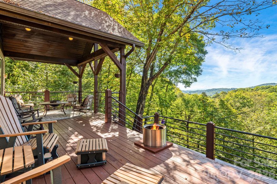 Perched at 4,100 feet inside Wolf Laurel’s 5,300 acre gated mountain community, 191 Ivy Way delivers the rare WNC combination buyers ask for again and again, year round, long range mountain views and flowing creeks across the property. Backing up to the Pisgah National Forest and set on six contiguous lots totaling 3.4 acres, this private retreat is surrounded by native rhododendron, hardwoods, wildflowers, and the peaceful sound of water below.
The four bedroom home is designed for comfortable year round living, with a welcoming foyer opening into a vaulted great room anchored by a dramatic floor-to-ceiling stone fireplace. Large windows frame layered Blue Ridge views, while the dining area and gourmet island kitchen offer granite countertops, gas range, generous storage, and easy gathering space. The main level includes the primary suite, media room, half bath, office, laundry, and expansive covered decks that live like outdoor rooms.
Upstairs are two additional bedrooms and a full bath, including a bedroom with private balcony overlooking the mountains and creeks. Wraparound decking offers sunny and shaded spaces for morning coffee, evening fire-pit gatherings, and quiet moments in the trees. The oversized two bay garage features higher clearance doors for larger vehicles, plus room for a workshop or game area, complete with a wood stove for winter months. One bedroom with ensuite full bath and bonus room provide flexible overflow guest space. Furnishings convey for an easy turnkey handoff.
Equity Village Club Membership conveys, offering access to the pool, pickleball, tennis, sports courts, playground, pavilion, stocked trout pond, and event center. Optional Wolf Laurel Country Club membership adds the beautiful 5 star golf course, dining, bar, 24 hr fitness center, and club amenities. Enjoy 50 miles of internal hiking trails, multiple Appalachian Trail access points, Hatley Pointe skiing, Smoke & Timber dining, and the magic of a true high-elevation mountain lifestyle.