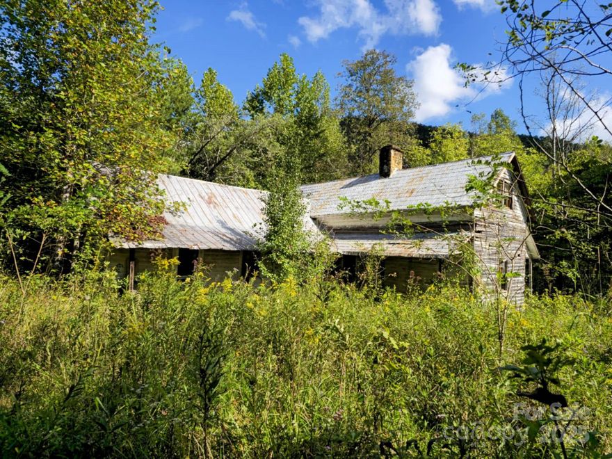 Tucked away in the quiet foothills of North Carolina, this 158-acre property feels like a step back in time — where mornings start with the sound of a creek rolling over smooth stones, and the world feels a little simpler.

As you wind down the old gravel path, the trees open just enough to reveal a weathered but sturdy homesite — a piece of local history that’s aged gracefully. The front porch looks out over the creek, where frogs sing at dusk and the soft rush of water carries through the valley. Generations have hunted these ridges, raised families here, and shared stories by the fire. The old two-seater outhouse still stands — a small but honest monument to simpler days.

While some of the terrain rises steeply into hardwood ridges, the property offers plenty of gentle knolls and accessible homesites — each with its own character and sweeping views that stretch across Rutherford County’s foothills. The possibilities are endless: a mountain retreat, hunting preserve, family compound, or simply a place to escape and breathe.

Power is already on-site, running to the existing homesite. The land is unrestricted, so your vision — whether a rustic cabin, dream home, or weekend getaway — can take shape without limits.

Though it feels miles from everything, you’re only a short drive from Rutherfordton’s conveniences, and less than an hour from Asheville, Hendersonville, and Spartanburg. Here, you can live off the beaten path without being out of reach.

This isn’t just a piece of land. It’s 158 acres of North Carolina heritage — quiet, private, and full of stories waiting to be told again.