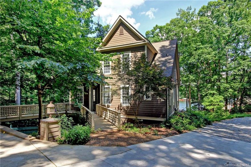 Real SHOW STOPPER! Adorable English cottage on Lake Norman located on main side-channel w/year-round view. Small, picturesque lagoon w/approx depth of 36", on lower side of waterfront, perfect for play & fishing. Beautiful low-maintenance gardens in natural setting. House boasts gorgeous heart-of-pine flooring, 2 screen porches & covered deck (1 on each level), 5 fireplaces & chef's kitchen. Half of lower level has HVAC & wiring but not finished. Large garage w/ fabulous workshop above. DREAMY!