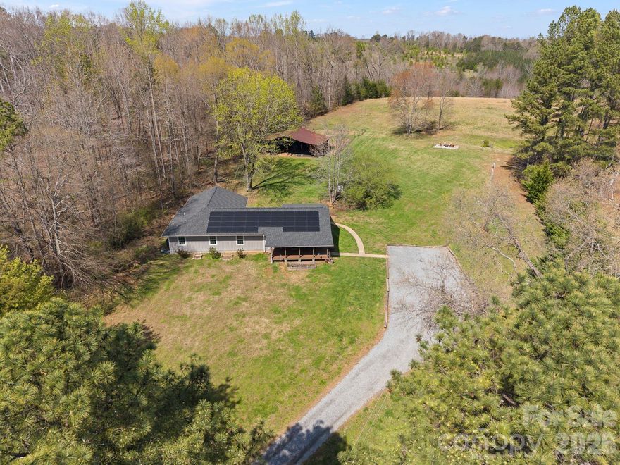 Set on over six picturesque acres, this beautifully reimagined single-level home offers the perfect blend of modern comfort and pastoral beauty. Originally built in 1987 and thoughtfully expanded and fully renovated in 2023—with an additional 1,100 square feet added—this property lives like new while retaining the warmth of an established setting.

Inside, the expansive great room welcomes you with an open, airy feel—ideal for both everyday living and entertaining. The heart of the home is the stunning kitchen, anchored by an impressive 8-foot island, creating a natural gathering space for family and guests alike.

The flexible floor plan features five bedrooms and four baths, including two private ensuite retreats—offering both comfort and versatility for multi-generational living or hosting.

Step outside and experience the true magic of this property. Approximately three acres are cleared and ready for pasture, a riding ring, or other outdoor pursuits, while an additional acre of preserved woodland showcases rare native flora,  Evenings are best spent by the firepit under a canopy of stars—free from city lights and perfect for stargazing.

Equestrian and hobby enthusiasts will appreciate the well-equipped 1,200-square-foot pole barn, complete with electricity, water access, a 30-amp plug, and a large walk-in chicken coop and run.

Enjoy the outdoors year-round from the spacious front and rear porches, both finished with low-maintenance TREX decking and surrounded by established landscaping featuring hydrangea, hosta, iris, lily, dahlia, wisteria, and jasmine.

Ideally located just 2.3 miles from the renowned Tryon International Equestrian Center.  See Features List for many more details of what this captivating property offers.