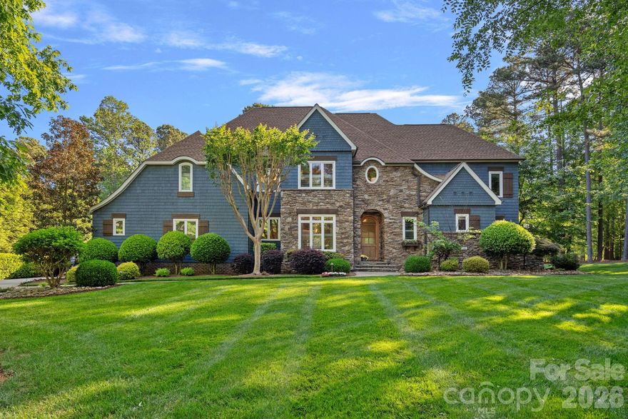 Set on a beautifully landscaped corner lot in a highly sought-after community, The Point, this exceptional home offers a refined blend of luxury, comfort, and outdoor living, completed by a deeded boat slip (Pier X, Slip 16) for effortless access to Lake Norman. The striking exterior showcases navy-painted cedar shake with stone accents, cedar shutters, and a newer architectural shingle roof (2022), while the expansive natural stone patio and pool deck create a true backyard retreat. Enjoy a saltwater pool with spa and waterfall, outdoor kitchen with TEC infrared grill, granite countertops, and stainless amenities, plus a retractable awning, outdoor speakers, and TV mount—perfect for entertaining. The fenced yard is thoughtfully landscaped and backed by a wooded area for added privacy. Inside, the home features wide-plank hardwood floors, designer lighting, and soft neutral tones throughout. The spacious great room is filled with natural light from a wall of windows overlooking the pool and features built-ins flanking a gas fireplace. The gourmet kitchen is both beautiful and highly functional, offering custom cabinetry, a large island with seating, walk-in pantry, and premium KitchenAid appliances including a 6-burner gas range, cabinet-faced refrigerator, and a wine fridge. Just around the corner you’ll find a butler’s pantry with lit pull-out drawers plus a little coffee bar, also easily accessible from the formal dining room with beadboard ceiling and a beautiful light fixture. An inviting family room on the main level provides additional gathering space with nearby powder room. Upstairs, the expansive primary suite features a sitting area, spa-like bath with jetted tub and tiled shower, and a large walk-in closet. Secondary bedrooms are generously sized with connecting baths, and a versatile bonus room offers ideal space for a media room, office, or both. Thoughtful touches in the hallway and landing make them both beautiful and functional spaces. Additional highlights include an oversized 3-car garage, updated HVAC systems (2023), Nest thermostats, irrigation, radiant barrier attic insulation, and abundant storage including about 180 square feet of additional storage on the upper level. This meticulously maintained home offers an exceptional lifestyle both inside and out, combining elegant design, thoughtful upgrades, and premier amenities in one of Lake Norman’s most prestigious communities.