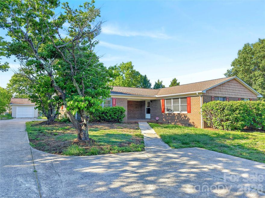 Tucked away on a quiet side street in Downtown Rutherford College, this well-maintained brick home offers the perfect blend of convenience, comfort, and functionality. Located just minutes from I-40, city parks, Lake Rhodhiss, Morganton, and Hickory, you’ll enjoy peaceful living without sacrificing accessibility.

Step inside to an inviting open-concept layout featuring a spacious living, dining, and kitchen area designed for both everyday living and entertaining. The kitchen is truly the heart of the home with stainless steel appliances, ceramic tile flooring, a large center island, and an entire wall of beautiful cabinetry providing an incredible amount of storage and workspace.

The split-bedroom floorplan offers added privacy, while the flexible third bedroom — previously used as a beauty shop — still retains plumbing connections and includes an attached half bath, making it ideal for a home business, guest space, office, or hobby room.

Additional updates include updated lighting and plumbing fixtures, a 30-year roof, and HVAC installed in 2010. You’ll also appreciate the oversized laundry room, abundant storage throughout, attached and detached garages, and ample parking space for guests, hobbies, or recreational vehicles.

Outside, enjoy a large private backyard perfect for relaxing, gardening, entertaining, or simply enjoying the quiet surroundings. This property offers easy maintenance and comfortable one-level living in a highly convenient location.