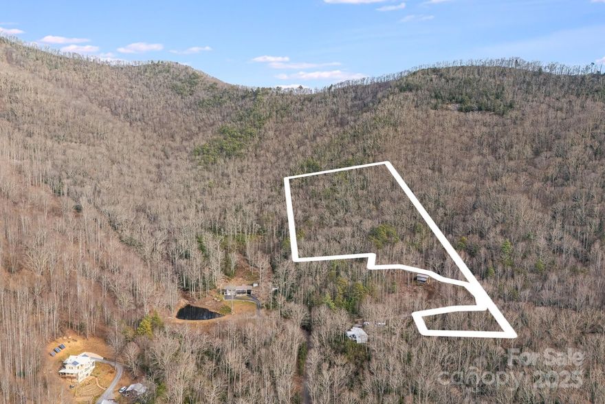Ranging from approximately 3,150’ to 3,850’ in elevation, this ±8.5-acre offering represents a pristine portion of a larger ±18.27-acre gated mountain sanctuary in the coveted North Fork Valley/Asheville Watershed. Exceptionally private yet remarkably convenient, this tract lies just minutes from downtown Black Mountain—named “America’s Prettiest Small Town”—and a short drive to Asheville and the Asheville Regional Airport.

This exceptional property provides stunning sunsets and sweeping west-facing views toward the Asheville Watershed, Blue Ridge Parkway, Craggy Gardens, and the surrounding mountain ranges. As elevation increases, the scenery becomes increasingly dramatic, with year-round vistas achievable through selective clearing. Mature forest and lush rhododendron ensure enduring privacy and serenity, creating a tranquil, cool-elevation retreat that feels worlds away.

The land adjoins conservation acreage, a 123-acre tract protected by the Southern Appalachian Highlands Conservancy. This rare positioning enhances seclusion and offers direct access to rich biodiversity and old-growth woodland—ideal for hiking, exploring, and experiencing the region’s natural abundance. Multiple potential building sites exist across the sloping-to-steep terrain. Walker Mountain Lane, a well-maintained gravel roadway, provides smooth, reliable access, with no need for four-wheel drive. The 16x16 shed on the property offers ample storage options. 

If the buyer elects to purchase only this ±8.5-acre portion of the ±18.27-acre parcel, a new survey will be recorded with Buncombe County prior to closing, which will establish an easement across this tract to provide access to the remaining acreage.

Just 10 minutes away, Black Mountain offers a vibrant complement to the property’s pristine solitude. This artistic enclave—once home to the iconic Black Mountain College—buzzes with creative energy. Its walkable downtown is filled with galleries showcasing local craftsmanship, cozy bistros serving mountain-inspired cuisine, and a deep sense of culture woven throughout.

Whether envisioned as a private estate, second home, or mountain retreat, this cool-elevation oasis offers unmatched privacy, dramatic scenery, and close proximity to one of Western North Carolina’s most inspiring small towns. No drive-bys due to gate.