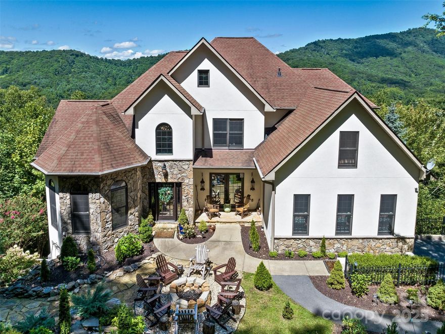 Welcome to this majestic mountain chateau with sweeping 180º views. Enjoy peace and tranquility with the sound of a soothing waterfall. This home is an ideal family vacation home or for the discerning buyer looking to entertain guests. Savor crisp mountain air around the fire pit or outdoor fireplace. Inside, a two-story foyer and great room with wainscoting and gleaming hardwoods set the tone for refined living. Floor-to-ceiling windows frame breathtaking vistas. The main-level primary suite offers a tranquil retreat, while a cedar-accented tavern provides a warm space for gathering. The newly updated kitchen features Quartz counters an induction range with double ovens. With four bedrooms and two guest suites, there’s room for everyone. The lower level features a game room, exercise room, bonus/bedroom, and additional guest suite—ensuring space and privacy. Hookups for a second laundry or future kitchen add flexibility. Experience the allure of this remarkable mountain home.