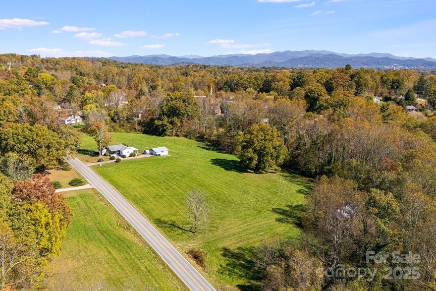 Prime Development Opportunity: 11.73 Acres with Mountain Views close in to Asheville.
Rare offering in one of Asheville's fastest-growing corridors. This 11.73-acre property sits just outside city limits with exceptional access to Patton Ave and I-40, positioning it perfectly for residential or mixed-use development.

Property Highlights:
1,200+ feet of road frontage on Holbrook Rd
5 acres of level, cleared pasture ready for development.
Stunning mountain ridge views.
Two parcels (PINs): 1.57-acre homesite + 10.16-acre pasture
3BR/1BA, 1,226 sq ft rock cottage on-site (vacant Nov 1)
Held by same family for 60+ years

Development Potential:
The cleared, level topography and extensive road frontage offer flexible subdivision possibilities. Combine with the adjacent 21-acre parcel (MLS# 4049531) to create a premier 32.82-acre assemblage with unmatched development upside in this high-demand market. Public utilities nearby.