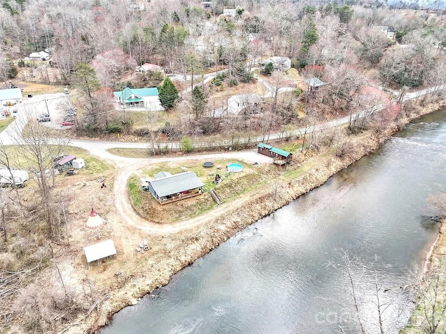 Dreaming of a mountain cabin on the water with plenty of room for a garden and room for a few rental units for extra money?  Want convenience to shopping, restaurants, schools and paved road access?   How about all of that and water, sewer, state maintained roads?  This is your opportunity!

Exceptional river frontage property offering in the mountains of western North Carolina!  This level 1.67 acre parcel with a cabin overlooking the river features 400 feet of frontage on the beautiful Tuckaseegee River, popularly referred to as "The Tuck".   Featured as a primary river for rainbow trout dry fly fishing, the Tuck is a year round outdoor recreation destination.  

Ideally positioned in Dillsboro area on North River Road (NCSR 1359) and just off US23/441, the primary north/south roading leading from Atlanta to Cherokee, the Great Smoky Mountains National Park and the Asheville area.  Dillsboro is the intersection of 23/441 and US 74, the Great Smoky Mountains Expressway.  The property's location  combines easy accessibility with privacy in a scenic setting along the river but features water and sewer served by the Tuckaseigee Water and Sewer with four (4) taps in place.

The parcel's flat topography, expansive river frontage and generous road frontage creates a compelling canvas for a boutique lodge, riverfront nursery, curated short-term rental concept or private estate.  The choices are unlimited.  While the property adjoins both of the towns of Dillsboro and Sylva, there is no zoning, allowing a broad range of residential options and affordability with no municipal taxes!  

Present uses of the property include a park model rental which has produced a substantial income in a modified short term rental (3 months and longer).  The owners have a two bedroom, two bath cabin overlooking the river and features a covered porch with hot tub overlooking the river.  The river frontage area has  been terraced down to the river and is included in the flood plain but the great majority of the property is high enough not to be in the food plain.  Hurricane Helene's heavy rains brought the water level up and into the terraced areas but did not encroach onto the level parts of the parcel!

Opportunies offering this combination of infrastructure, road and river frontage, location and flexibility along the Tuckaseegee River are rare and this presents both a lifestyle asset and a compelling long-term investment.