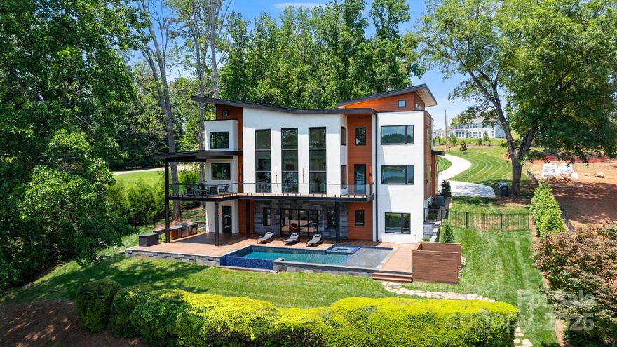 Experience lakefront luxury just 20 minutes from uptown Charlotte at 5930 Midsomer Road. This custom-built, four-bedroom, four-full-bath, two-half-bath home on Lake Wylie features high-end finishes, including smooth hard-coat stucco, Balinese lava stone, and exotic cumaru wood. Enter through an 8-foot glass door to soaring 22-foot ceilings and panoramic lake views. The open-concept living room features floor-to-ceiling windows and a striking stone fireplace. The chef’s kitchen offers Monogram appliances, a 10' waterfall island, and opens to a covered outdoor kitchen and patio. Main-level primary suite includes lake views, deck access, and a spa-like bath with wet room and freestanding tub. The walk-out basement includes a full bar, guest suite, and seamless access to the resort-style infinity pool, spa, and tanning ledge. Additional features: outdoor shower, built-in grill, and private dock with boat lift. This is lakeside living redefined!