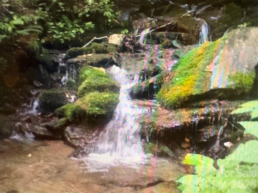 Discover an established view lot featuring not one, but two picturesque cascading streams! This property includes an excavated homesite and driveway. A quick hike through the woods will take you down to a lively, rushing stream. Enjoy the soothing sounds of the creek below while taking in breathtaking mountain views from the top! The lot offers gated and paved access, ensuring both security and convenience. Located in a peaceful country setting, it remains just a short drive from Bryson City and all the area’s top attractions. Please note: the included photos were taken when the lot was initially cleared several years ago; the land is now naturally overgrown, providing extra privacy and a lush, wooded atmosphere. All of this on 3.73 acres—offering you even more privacy and space to enjoy the tranquil setting.