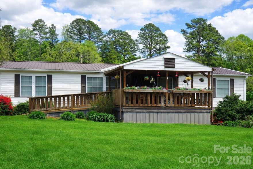 Well-maintained doublewide on a flat 1-acre lot — 3 bedrooms, 2 baths — move-in ready. Features a durable metal roof, bright open living area with a large kitchen bar perfect for meal prep and entertaining, and a separate laundry room for added convenience. Large primary en suite includes double vanity, jetted tub, walk-in shower and spacious walk-in closet. Enjoy covered front and back porches, a storage building, plus a 2-car detached carport with additional storage. Quiet, level property with plenty of yard space — ideal for country living or outdoor activities.