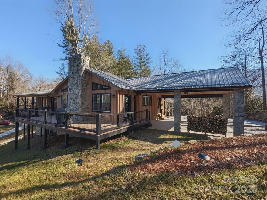 Pinewood Lodge a Beautiful Custom built home (2022) with long range views minutes from Waynesville. This stunning property is a Vacation Rental with a proven track record. Open Ranch plan, 3 BR/2.5 Baths, 2 Car Carport, Lots of windows and natural light, simplicity in one level living.  Gourmet KT open to massive Great Room. Great room w/ custom stone hearth and fireplace w/ gas logs leading to wrap around deck perfect for entertaining. Powder room off GR. Open kitchen with vaulted ceilings, custom cabinetry, large stainless sink, cast concrete countertops, stone backsplash, high end stainless steel appliances, kitchen island with bar seating, and a 4.8x10 pantry. Durable vinyl plank flooring throughout. Owners suite w/ gas fireplace, vaulted ceiling, walk-in shower w/custom stonework and bench seat, Double vanities, cast concrete countertops, walk-in closet and private door to covered porch.  Guest bath with clawfoot tub custom sink stonework. Firepit area. Furniture negotiable.