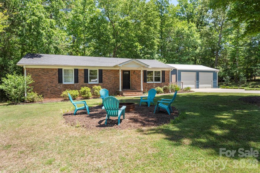 Tucked at the end of a quiet cul-de-sac, this updated 3-bedroom, 2-bath brick home delivers privacy, space, and flexibility—without HOA restrictions—on a level, tree-lined .66-acre corner lot. 
Step inside to a bright, open living and family area with bamboo flooring, recessed lighting, and an easy, natural flow into the kitchen—the true centerpiece of the home. Thoughtfully designed, the kitchen features quartz countertops, a breakfast bar with built-in cookbook storage, and lighted display cabinetry with upper accent lighting. High-end appliances include an 800 Series Bosch dishwasher, Thermador gas cooktop with exterior-vented hood, double ovens, and an upgraded microwave—ready for both everyday living and entertaining. 
The home offers three comfortable bedrooms and two full baths, along with key updates like a newer heat pump and improved ductwork for added efficiency and peace of mind.
Outdoors is where this property really sets itself apart. The spacious corner lot is lined with mature trees and includes producing fruit trees—apple, peach, and plum—plus blueberry bushes. A detached two-car garage (added in 2017) with roll-up doors and a side porch entry adds both function and charm.
Enjoy a quiet, tucked-away setting while staying close to everything—just 20 minutes to Lake Wylie, Belmont’s shops and restaurants, and Steele Creek.
Note: SCDHEC was unable to locate septic records due to the age of the property.