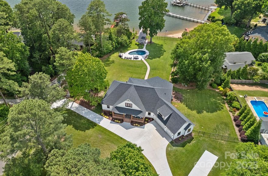 Highly sought after Isle Of Pines ranch on 1.5 acres of Lake Norman's stunning shoreline! This expansive home features 106 feet of waterfront, a sandy beach, breathtaking sunsets, and a saltwater Pebbletec pool. The property includes a charming lakehouse with storage for pool and lake fun, plus a bathroom. Inside, enjoy four en suite bedrooms, an office/optional bedroom, and a spacious bonus room above the oversized three-car garage. The gourmet kitchen is a chef's delight, featuring quartz countertops, stainless steel appliances, a Wolf 48-inch gas range, three ovens, and a custom range hood. The home boasts all-new lighting, remote blinds, custom closets, and 11-foot ceilings. Entertaining is a breeze with a built-in bar with wine and beer refrigerators. A Butler's pantry is equipped with a full-size refrigerator, sink, dishwasher, and granite counter top for meal prep. This property offers luxurious living, endless opportunities for lakeside enjoyment, NO HOA and a builder warranty.