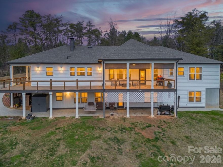This custom 2020 home with a modern farmhouse feel offers over 5,000 square feet of living space on 1.83 private acres with year-round long-distance views, and only 25 minutes from Asheville. The main level features two kitchens, a spacious primary kitchen with marble countertops, custom cabinetry, stainless appliances, subway tile and a large eat in island, plus a fully equipped prep kitchen. The home includes five bedrooms and six baths with four en suite. Nine-foot ceilings throughout enhance the open design. The lower level recreation room features a stone wood-burning fireplace, workshop and third kitchen area with select appliances in place. Wraparound porches and decks create an expansive outdoor living space, ideal for entertaining or intimate moments. An inviting open yard with vegetable beds provide plenty of room for gardening, beekeeping, animals, playgrounds and outdoor gatherings in a private rural setting.