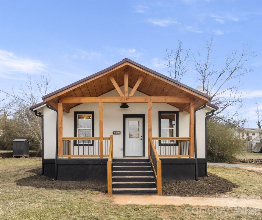 Positioned in the heart of downtown Rutherfordton, this beautifully remodeled bungalow offers the rare combination of charm, quality and walkable small-town living. Thoughtfully renovated from top to bottom, the two-bedroom, one-bath home lives large in 1,000-plus square feet, highlighted by a showstopping living room with vaulted, exposed-beam ceilings and a charming fireplace. High-end finishes include luxury vinyl plank flooring, solid-surface countertops, custom cabinetry, a deep kitchen sink, rustic statement hood, dedicated laundry room and tasteful barn door accent. The extensive remodel features all new plumbing, electrical, windows, metal roof, gutters, stucco siding and an efficient HVAC system, delivering near new confidence at an approachable price point. A covered front porch with post-and-beam accents and a level yard create inviting outdoor spaces. Directly across the street, Kiwanis Park offers playgrounds, dog park, green space and access to Purple Martin Greenway, while downtown shops, restaurants and local events are just a short distance away. Centrally located with easy access to Asheville, Hendersonville, hospitals and regional airports, this home is ideal for those seeking lifestyle, comfort and everyday convenience.