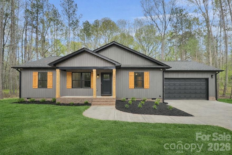 Welcome to this beautifully built new construction ranch home, offering thoughtful craftsmanship and timeless style on a peaceful 1-acre wooded lot in an established neighborhood with no HOA. Step inside and you’ll immediately appreciate the open-concept design and natural light that fills the space. The spacious living area that flows seamlessly into the modern kitchen, complete with lovely natural wood toned soft close shaker cabinets, quartz countertops, a large island, and stainless steel appliances. The home includes 3 bedrooms and 2 full baths, offering a split bedroom layout and comfortable one-level living. The primary suite provides a serene retreat with an en suite featuring a dual vanity, walk-in closet, and a beautifully tiled shower. Outside, enjoy the quiet setting from your covered front porch or rear deck—perfect for relaxing or entertaining while surrounded by nature. The attached two-car garage provides convenience and extra storage space. Located in North Lancaster, you’ll love the peaceful setting while still being conveniently located from shopping, dining, and schools—plus easy access to Indian Land, Rock Hill, and South Charlotte.