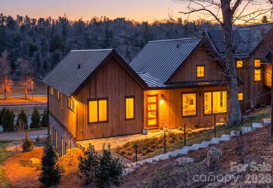 Set along the banks of the French Broad River and directly adjacent to Olivette’s private riverfront park, this exceptional home offers a rare opportunity to experience true riverfront living in one of Asheville’s most sought-after communities. With river views from nearly every room, the connection to water, light, and landscape is immediate and unforgettable.
Thoughtfully designed by Brent Campbell & Associates and built by JAG Construction, the home blends refined architecture with effortless livability. Vaulted tongue-and-groove ceilings, custom railings, and curated designer lighting create a sense of warmth and artistry throughout. The open-concept floor plan flows beautifully to a spacious back deck—perfect for entertaining or simply taking in the ever-changing river views.
The chef’s kitchen is both functional and striking, featuring custom cabinetry, high-end finishes, and a bold, thoughtfully designed palette. Built-ins throughout the home add both character and convenience, while hardwood floors and beautifully selected tilework reflect a level of detail that is rarely seen. The primary suite is a private retreat with a serene en-suite bath and elevated finishes that feel both luxurious and grounding.
An elevator provides easy access between levels, and the oversized two-car garage offers ample storage. Geothermal heating and cooling ensure exceptional energy efficiency and low operating costs.
Beyond the home, the Olivette lifestyle unfolds. This award-winning agrihood is centered around a working organic farm, with seasonal produce, community gatherings, and a deep connection to land and place. Residents enjoy miles of trails, multiple parks, river access, and a vibrant calendar of events—from riverside concerts and farm dinners to casual evenings with neighbors. Thoughtfully designed for walkability and connection, Olivette offers a rare blend of privacy, community, and outdoor living just minutes from downtown Asheville.
For those seeking a truly special home on the river—one that pairs exceptional design with an extraordinary lifestyle—this is a rare and compelling offering.