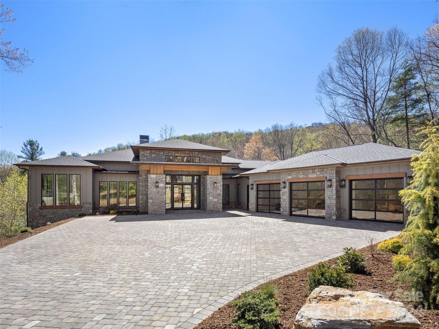 Welcome to the ultimate in modern luxury new construction at The Cliffs of Walnut Cove. The thoughtful architecture of this home makes it ideal for enjoying a blend of indoor and outdoor living. The expansive great room with 16' ceilings opens up to a peaceful wooded setting and amazing entertainment spaces which include multiple decks and an impressive outdoor kitchen. From the high-end finishes, soaring fireplaces, Thermador appliances and beautiful modern selections that include custom built-ins and two luxurious spa-like en-suites. The builder spared no expense! This home also includes an elevator and a fully finished basement with a well appointed 2nd living quarters. Located within walking distance of the wellness center, with a Cliffs membership, you can enjoy all community amenities including golf, tennis, pool, gym, and more. Photos of interior are renderings and will vary slightly when finished.