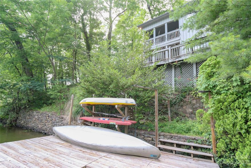 Charming vintage lake cottage with great parking!  The cottage is privately situated with pretty views of the lake and mountains. Private dock. The main entry floor has a living room with a fireplace, primary bedroom, full bath, sleeping porch (flex space), and covered porch.  The lower level lakefront has a spacious and modern kitchen, eating area, laundry, and half bath, and tucked near stairs is an additional sleeping area.
The outdoors offers a large deck accessed from the kitchen and lower level, an outdoor cooking area, and a large dock with boat slip on the water.  The views are southwest and the cottage is tucked safely inside a large cove with open water just a few yards away. Short drive to shopping, groceries, Chimney Rock State Park, The Tryon International Equestrian Center, Hendersonville, Asheville, and The Blue Ridge Parkway.