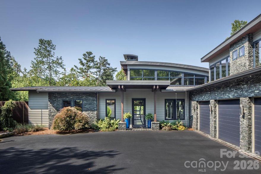 Gracefully poised in the prestigious gated community of The Ramble Biltmore Forest, this stunning contemporary masterpiece blends modern elegance with warm hospitality. Designed with extraordinary attention to detail, the residence is defined by soaring ceilings, walls of glass and a sculptural marble fireplace, all set against the dramatic beauty of ebonized bamboo floors. The gourmet kitchen is a work of art and function, anchored by a new 48-inch Fulgor Milano Sofia range, Brazilian granite countertops and backsplash, extensive custom cabinetry, and extra-heavy drawers designed to accommodate cast iron and Le Creuset. Three Murano glass pendants illuminate the island, while a butler’s pantry with second refrigerator adds convenience. Under-cabinet angle power strips, an oversized three-car garage wired for two EV charging stations, and updated 2024 openers underscore the thoughtful design. The main-level primary suite offers a spa-inspired bath with dual Kohler shower systems, a rain head, and radiant-heated floors, complemented by a custom walk-in closet with floor-to-ceiling built-ins. A private fenced terrace with synthetic turf creates the ideal sun lounge or dog run. A second-floor guest suite provides three gracious rooms with kitchenette and private entry, ideal for extended stays. Additional highlights include a wine keeper wine room awaiting enclosure, two tankless water heaters with recirculation, a 2024 HVAC system with five zones, Trane XR whole-house filtration and humidifier, AT&T high-speed fiber, and an Eaton whole-house generator. Smart living is ensured with Control4 and Lutron automation, 14 audio zones and a monitored security system. Seamless indoor-outdoor living defines the home. A phantom-screened porch with fireplace opens to the manicured pool area, complemented by an outdoor kitchen that rivals the indoors with a Fire Magic Echelon grill, infrared sear and rotisserie, and Earth Stone 90 wood or gas pizza oven. Multi-zone landscape sprinklers with remote access, a separate irrigation meter and hot tub complete this private outdoor sanctuary. Beyond the residence, life in The Ramble is enriched by world-class amenities. The Living Well Center, a 9,000-square-foot gathering place, offers a heated saline pool, fitness center, pickleball courts, and great room with stone fireplace and curated art collections. Buck Spring Cabin, once part of George Vanderbilt’s rustic retreat, now serves as a hub for book clubs, card games and resident events. Longmeadow Park is the community’s grand outdoor living room, featuring a natural amphitheater, open-air pavilion, formal English gardens, a playground, basketball court, multi-purpose field and a hand-hewn stone firepit. Over seven miles of wooded trails, along with Overlook Park and Crescent Park, invite daily connection with nature. This residence is more than a home—it is a work of art, combining architectural distinction with state-of-the-art systems and the enduring elegance of The Ramble. Here, every detail is refined, every amenity considered and every day elevated by the beauty of Asheville’s exclusive community.