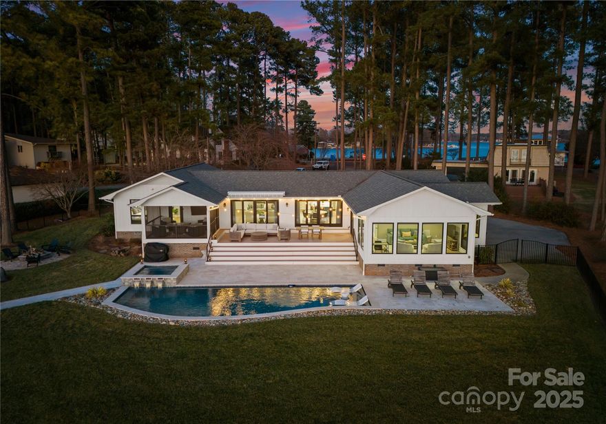 Nestled along the tranquil shores of Lake Norman, this stunning lake house blends modern elegance with lakeside charm. Sweeping water views from nearly every room create a serene backdrop, while the open-concept design brings the outdoors in, making it an entertainer’s dream and a peaceful retreat. The heart of the home is its expansive living area, where the kitchen, dining area, and living rooms flow together. Oversized windows and sliding glass doors flood the space with natural light, framing lake views. The gourmet kitchen features stainless steel appliances, a spacious island with seating, and sleek custom cabinetry—perfect for cooking and socializing. The primary bedroom offers a private screened-in porch to relax lakeside. The ensuite bath is a spa-like retreat with dual vanities and a walk-in shower. Two spacious bedrooms provide comfort for guests, and a custom bunk room offers extra flex space. Large back deck, heated pool/spa complete the lakeside experience.