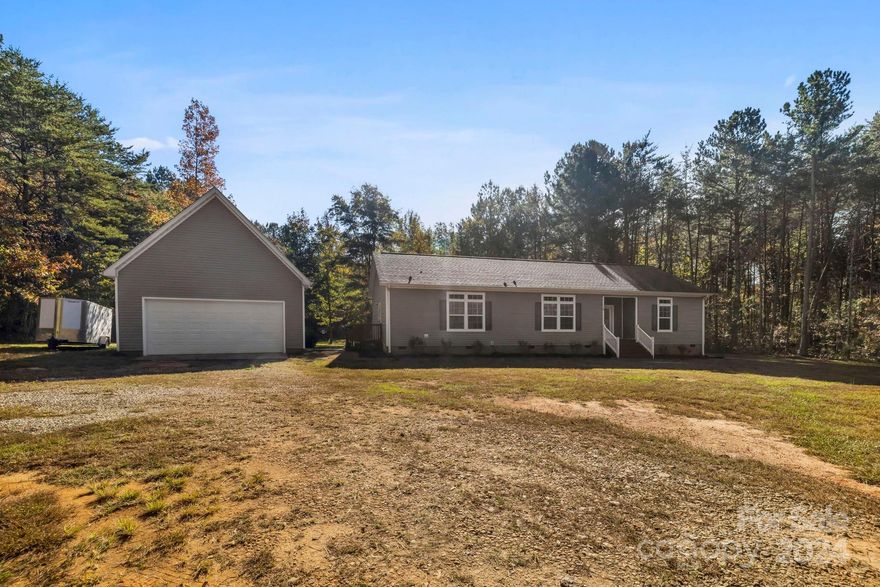 Nestled in the desirable Travelers Rest area is this unique modular home on 2.1 acres with no restrictions. This home offers both privacy and space with a long, private driveway leading to a peaceful setting. This property is complemented by a detached two-car garage/workshop with a second story, electricity, and side yard door literally steps away from the mudroom entrance to the home. Step through the front door to a quaint entryway, setting the stage for a charming rustic interior. The open-concept layout connects the kitchen, living, and dining areas where you'll immediately notice coffered ceilings, wood beams, crown molding, and natural light. The living room boasts a floor to ceiling stone wood-burning fireplace. The kitchen is a dream featuring a large island, farmhouse sink with a view of the backyard, and all appliances. Sliding doors off the main area walk out to a deck overlooking a relaxing backyard. The primary bathroom is a must see, featuring a walk-in custom closet.