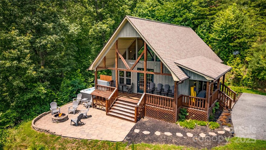 Welcome to Layer's View Lodge, your perfect getaway! This cabin offers breathtaking layered southern mountain views and glimpses of the Tuckasegee River, particularly stunning in the Fall and Winter. Experience the magic of the outdoor spaces featuring a fire pit, a soothing hot tub, and a lovely patio—each framed by spectacular scenery. The inviting covered front porch is the ideal spot for unwinding and soaking in nature's wonders. Inside, a wall of windows fills the cabin with natural light, complemented by soaring vaulted ceilings and a warm gas log fireplace. The kitchen, equipped with stainless steel appliances, pairs beautifully with two spacious bedrooms and two bathrooms, ensuring comfort at every turn. Thriving as a vacation rental, Layer's View Lodge represents not only a wise investment but also a peaceful retreat for you and your family. Seize this extraordinary opportunity today! With paved access just minutes to Dillsboro, Sylva, Franklin, and all of the area attractions