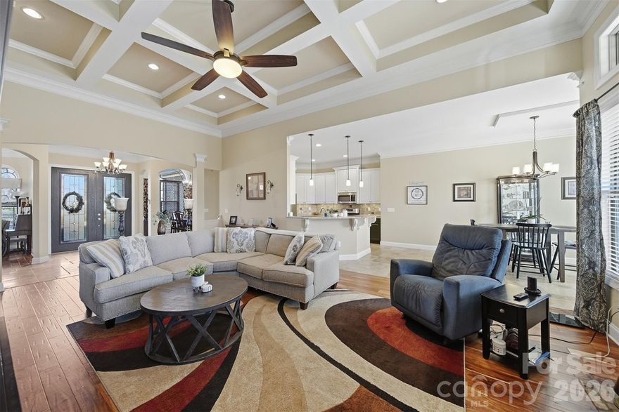 This gorgeous home blends timeless style with quality craftsmanship. The open-concept great room boasts a dramatic coffered ceiling, rich Exotic Acacia hardwood floors, gas fireplace and plenty of natural light. The living area flows easily into the kitchen, which offers soft-close cabinetry, generous counter space, a large center island, stone flooring and chic pendant lighting. The dining room features graceful arched openings, crown molding, and a tray ceiling, perfectly connected to the main living spaces. The primary suite is a private haven with a tray ceiling, Exotic Acacia floors, a custom tile walk-in shower with stone accents, and a decorative mosaic inlay. A split-bedroom layout offers extra privacy, with a shared bathroom featuring dual access. Spacious bedrooms enjoy natural light, ceiling fans, and ample closets. Upstairs, a large bonus room can serve as a gym, playroom, office, or multi-generational space. Outside, the curb appeal shines, complemented by a spacious crawlspace over 5' tall for stand-up access, great storage, and block pier support with vapor barrier coverage. Beautifully maintained and thoughtfully designed, this home offers comfort, style, and quality in every detail. The property lines run beyond the black rod iron fencing on both sides. Please see approximate property lines in photos.