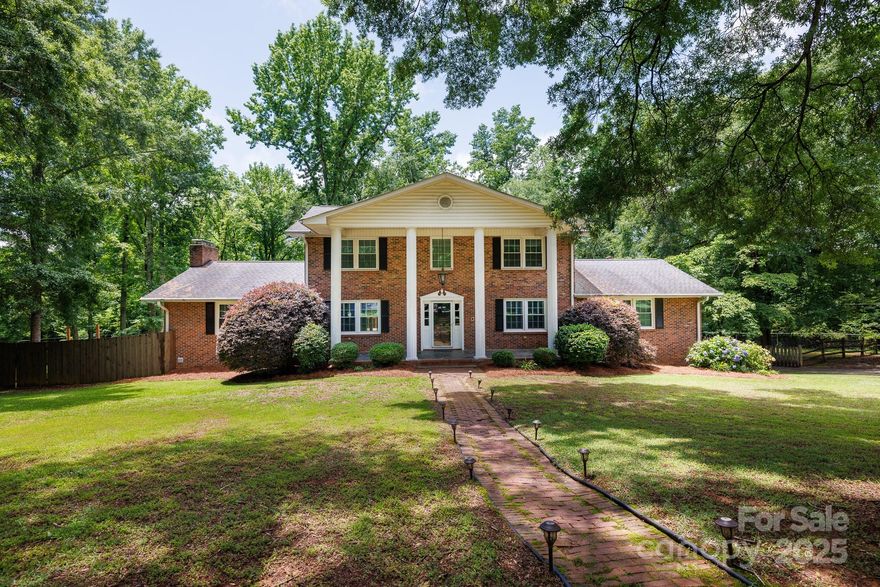 Tucked away on a quiet cul-de-sac in an established neighborhood, this full-brick home sits on 1.95 acres. The finished basement features a full secondary living quarters with a private entrance—perfect for multigenerational living or guests—complete with a spacious living area, full kitchen, bedroom, full bath, and laundry. The main home includes 4 additional bedrooms and 3 full baths, including a main-level guest suite. You'll find a dedicated office, family room, formal dining room, and a showstopping great room with reclaimed hardwood floors from a historic school gym. The kitchen is well-appointed with granite counters, a pantry, dining area, and double oven. A bright sunroom adds to the charm, while the basement also offers ample unfinished storage. Outdoor living shines with multiple decks, a fenced backyard, heated pool, and a wide front porch. Conveniently located near shopping and dining, this home is a must-see for anyone seeking space and comfort with character.
