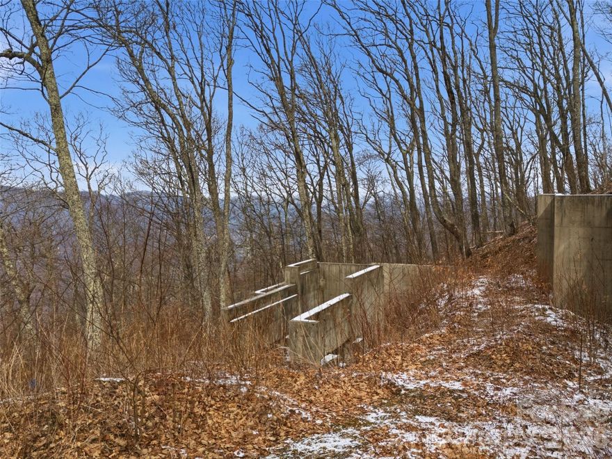 Discover this exceptional parcel in the prestigious Smoky Mountain Retreat at Eagles Nest, a gated community with paved access and breathtaking high-elevation views. Ideally positioned near the development’s topside secondary gate, this lot offers convenient access to both Maggie Valley and the Laurel Ridge/Waynesville area, blending privacy with accessibility. Sitting at nearly 4,400 feet in elevation, you’ll enjoy cooler summer temperatures, fresh mountain air, and the potential for stunning long-range vistas. A poured-wall foundation is already in place—saving you time and expense—and custom build plans are available to help bring your mountain dream home to life. Additional features include city water and Spectrum fiber optic service, providing modern convenience in a serene mountain setting. Residents enjoy outstanding community amenities, making this a rare opportunity to build in a prime Haywood County location with much of the groundwork already complete.