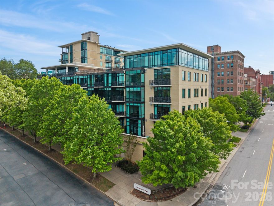 Experience the pinnacle of refined city living in this meticulously designed corner residence at one of Asheville's most coveted addresses. Situated on the third floor of the prestigious 60 N. Market building, this expansive three-bedroom, two-and-a-half-bathroom condo offers over 1,800 square feet of sophisticated interior space paired with the effortless convenience of a lock-and-leave lifestyle.
The heart of this home is a light-filled open great room that seamlessly blends luxury and comfort. The kitchen serves as a focal point, featuring beautiful, custom wood cabinetry that provides both warmth and ample storage for the discerning chef. Throughout the living areas, the soaring floor-to-ceiling windows are dressed in exquisite custom silk drapes, adding a layer of timeless elegance and soft texture to the modern urban backdrop. With room for an office and guest ensuite, this downtown condo lives large. 
Residents of 60 N. Market enjoy access to premium amenities that elevate the downtown experience:

Rooftop Clubhouse: An expansive space for entertaining with a fully stocked kitchen, fireplace, and TV.
Rooftop Terrace: Outdoor sitting areas providing stunning panoramic views.
Fitness Center: A well-equipped on-site facility for health and wellness.
Security: Secure basement parking with elevator access directly to the second floor and dedicated ev charger for unit #217.
Adjacent to the Asheville arts scene, world class restaurants and music venues galore - what else can you ask for?