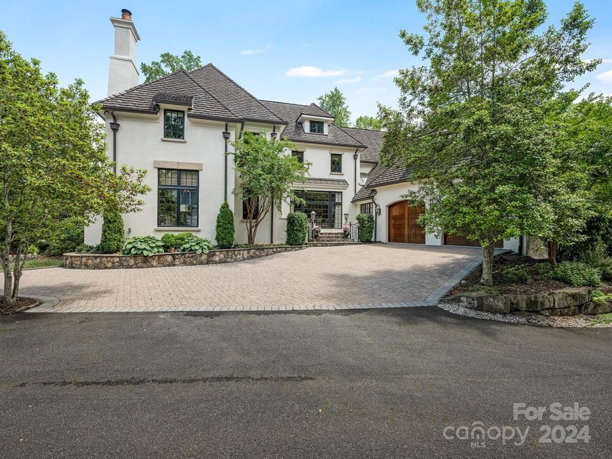 Tucked away in the heart of Eastover--overlooking Catawba Conservancy Land-this French country home blends charm with all of today's conveniences. The open floor plan is designed to flow naturally for easy entertaining.
Main level primary suite has an oversized bath, dual walk in closets and direct access to the terrace. The chef's domain features  a large island, professional grade appliances, pantry, dedicated breakfast area and bar. Coffered ceilings, built-ins, and the stone fireplace accent the great room position as the heart of the house.
The paneled office with fireplace and beamed ceiling is both inviting and is ideally  positioned to shield  the sounds of an active house.

Heading to the upper level--all bedrooms are en suite with oversized closets. Ample storage throughout--both walk in and walk up options.