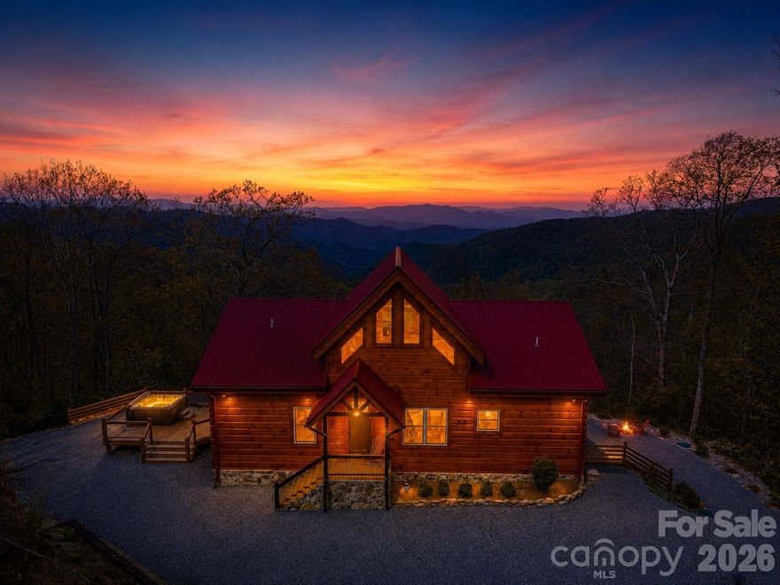 Custom-built real log cabin at 4,100 feet elevation in the prestigious Alarka Highlands community offering breathtaking long-range views w/ 7 mountain layers looking into the heart of Great Smoky Mountains National Park! This luxury 3BR/3.5BA retreat features soaring ceilings, walls of windows, distressed hickory floors & a stunning floor-to-ceiling stone gas fireplace in the great room. The chef’s kitchen includes high-end stainless appliances, gas range w/ double ovens, quartz countertops & abundant cabinetry flowing into the dining area. Split floor plan w/ 2 primary suites on the main level, each offering walk-in closets, tile showers & private deck access to enjoy the incredible views. Spacious loft provides flexible space for an office, bunk room, or sitting area. Finished basement is designed for entertaining w/ a 2nd fireplace in the family/game room, 3rd bedroom, full bath & walkout access to the covered patio & firepit. Expansive decking plus an oversized side deck w/ hot tub & grilling area create exceptional outdoor living spaces. Situated on 4.77 private acres w/ high-speed Balsam West internet & a 24KW Generac generator. Offered turnkey with high end furnishings!