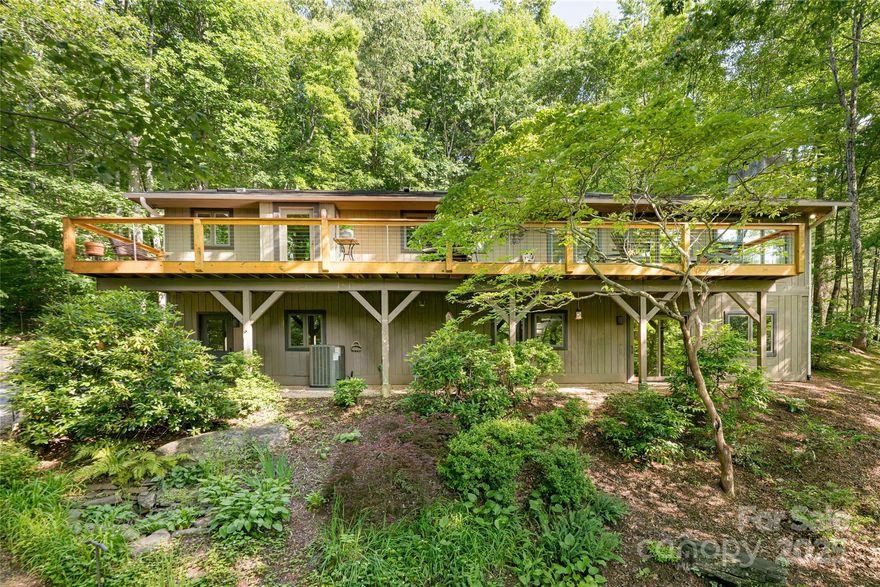 Tucked into a peaceful forest setting, this exceptional mountain retreat offers unrivaled privacy and a seamless blend of natural forest beauty and long-range views. Stone paths and an expansive outdoor deck invite tranquil outdoor living, enhanced by dual-zone landscape lighting. Inside, a chef's kitchen frames stunning mountain vistas and features a 6-burner Bertazzoni gas range, Forest Milwork cabinetry, quartz countertops and direct deck access. Just beyond, a chef's utility room offers a walk-in pantry with built-in cabinetry, 54-bottle wine cooler, sink, and laundry. The great room is warm and inviting with vaulted ceilings, skylights, a gas fireplace, and custom wood mantle. The dining room, adorned with Mobilia lighting, connects to the kitchen via a thoughtful pass-through. The main-level primary suite is a serene escape with forest views, jacuzzi tub, walk-in rain shower, and spacious closet. Hickory hardwoods flow throughout the main level, with polished concrete below.