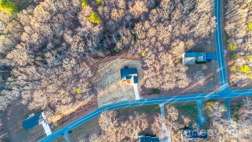 There is NO HOA for this new-construction home that sits on a full acre lot and is offering modern comforts, thoughtful design, and the serenity in this well-established neighborhood. Surrounded by mature trees and natural landscape, this 3-bedroom and 2-bath home combines clean, contemporary finishes with the peaceful feel of country living. Step inside to an open-concept layout anchored by a spacious great room and a well-appointed kitchen featuring quartz countertops, matching quartz-topped vanities, a large island, and stainless steel appliances. The dining area flows seamlessly to the rear deck, creating an effortless indoor/outdoor living experience ideal for gatherings, grilling, or quiet morning coffee overlooking nature. The split-bedroom layout provides exceptional privacy. The primary suite is positioned on its own wing of the home, complete with dual sinks, a walk-in closet, and generous natural light—perfect for retreat and relaxation. Bedrooms 2 and 3 are located on the opposite side of the home with a full bath and linen storage nearby, ideal for the family, guests, or a home office. Enjoy the charm of a covered front porch designed for neighborly conversation and seasonal decorating, while the back deck offers a secluded vantage point into the wooded surroundings. An attached two-car garage provides convenience, storage, and weather protection. With 1,416 sq ft of heated living area, a functional layout, and designer-selected finishes, this home is ready for its new family who is seeking comfort, privacy, and a connection to the outdoors—all while staying close to Claremont’s amenities and major routes. Schedule your showing today!