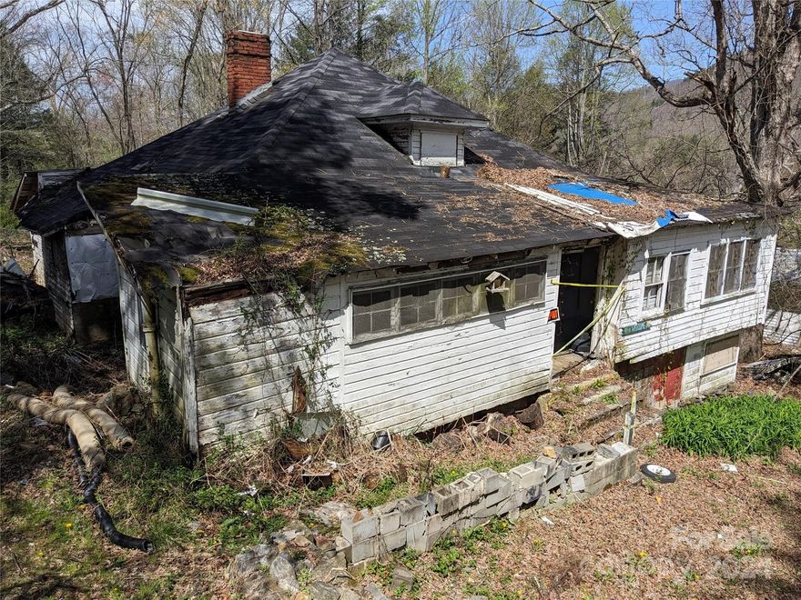 This Black Mountain home has seen better days - currently uninhabitable, but the established parcel has utilities and road access for redevelopment. There is no heating source and all doors have been removed. The roof has failed in multiple areas and floors are also compromised. The convenient location is easily accessible and very close to nearby downtown Black Mountain, Montreat College and all of the Ridgecrest retreat centers. The lot is about 90 feet wide by 85 feet deep. The current house footprint is roughly 50'x50'. Some mountain views are visible towards the back of the property. The neighbors would really like to see this property restored and bring value back to the community.