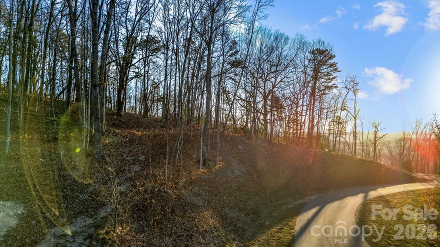 Discover Lot 9, this expansive and private homesite nestled within the iconic gated community of Couch Mountain. Located at 99 Spring Song Lane, this property features gentle to relatively flat topography, offering privacy and easy trail access. Enjoy the beautiful morning sunlight while being surrounded by nature. Couch Mountain is a 395-acre low-density community that provides residents with direct access to the outdoors. The community includes approximately four acres of hiking trails situated within a 138-acre Nature Preserve. Residents can spend their days in community gardens, explore the trails, and enjoy honey from the resident beehives. Conveniently located between Asheville and Hendersonville, this community offers easy access to both mountain towns.