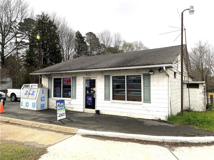 Level Commercial Site Zoned GC at the Five Points Intersection-approximately 677 feet of road frontage on 3 roads.
Block Building has approximately 1380 heated SQFT and approximately 323 unheated SQFT. Well & septic is located on the property. There are no bathrooms at the building. Mobile home beside the building has a septic tank. Building, Barn, & Mobile Home are being sold "as-is"