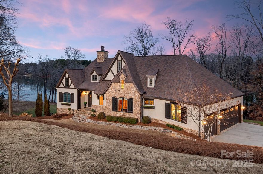 This European-inspired estate on Lake Wylie offers 3 bedrooms, 5 bathrooms, and 3,338 sq. ft. of living space. The main-level living room features cathedral ceilings with custom wood beams and a hand-applied glaze finish on the walls. The dining area boasts a plastered damask accent wall, complemented by custom draperies throughout. The gourmet kitchen includes Wolf appliances, custom cabinetry, and a solid carved stone apron sink.
The primary suite on the main level features lake views and a copper soaking tub. Each additional bedroom is also an en suite with lake views and walk-in closets. The main level also has a grand covered porch with stunning lake views. Downstairs features a game/entertainment area with wet bar, and private gym with a hidden bookshelf door leading to storage. This home also includes a three-car garage, floored attic space, and antique European chimney pots. Private dock with automatic boat lift completes this rare waterfront retreat. Schedule your tour today!