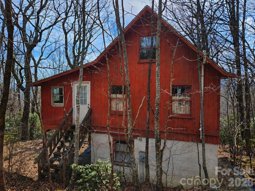 Tucked away on top of the ridge, at the end of the road, this cabin offers 3.54 peaceful, private and gently sloping acres and is ready for a complete renovation. The existing structure provides a solid starting point, with a kitchen, dining area, and full bath on the main level (all need full renovation), and a large open bedroom/sitting space upstairs. Upper-level porches extend from two sides, where the previous owner began enclosing portions to increase living space while preserving an open area to capture the property’s view potential. With selective tree clearing—primarily below the home—the setting could open up to showcase long-range views. A small outbuilding offers additional storage or workshop possibilities. Property is being sold as-is and will require significant updates and improvements—ideal for investors or buyers looking to create a custom mountain retreat. *A new roof was installed after Hurricane Helene but no repairs were made to the damage inside of the home. Community note: STRs not allowed. AWD/4WD recommended... Please call before driving by!