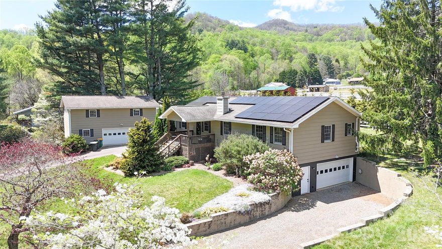 **Back on market due to buyer’s change in personal circumstances. No fault of seller and unrelated to the property.**  Set within a peaceful mountain valley just a short drive from downtown Waynesville and the Blue Ridge Parkway, this private retreat offers a unique and flexible multi-dwelling arrangement complemented by tranquil mountain views. The main residence features an open layout with vaulted ceilings, a gas-vented fireplace, and a main-level primary suite, while the finished lower level adds valuable living space along with a full bath.

Positioned above the detached two-car garage, a separate studio apartment of approximately 900 square feet includes its own kitchen, living area, private entrance, and dedicated septic system—well suited for guests, income potential, or extended living arrangements. The home is offered fully furnished at no additional cost, creating an easy, move-in-ready opportunity.

Energy efficiency is a notable highlight, with solar panels and a Tesla battery system helping keep power costs at or near zero for much of the year. Both the main home and the garage apartment benefit from separate septic systems, adding convenience and independence to the layout. Outdoor spaces include covered porches and deck areas designed to take in the surrounding scenery, all tucked along a quiet dead-end road for added privacy.

Blending versatility, thoughtful features, and a serene setting, this property offers comfortable mountain living with the added benefit of close proximity to town.