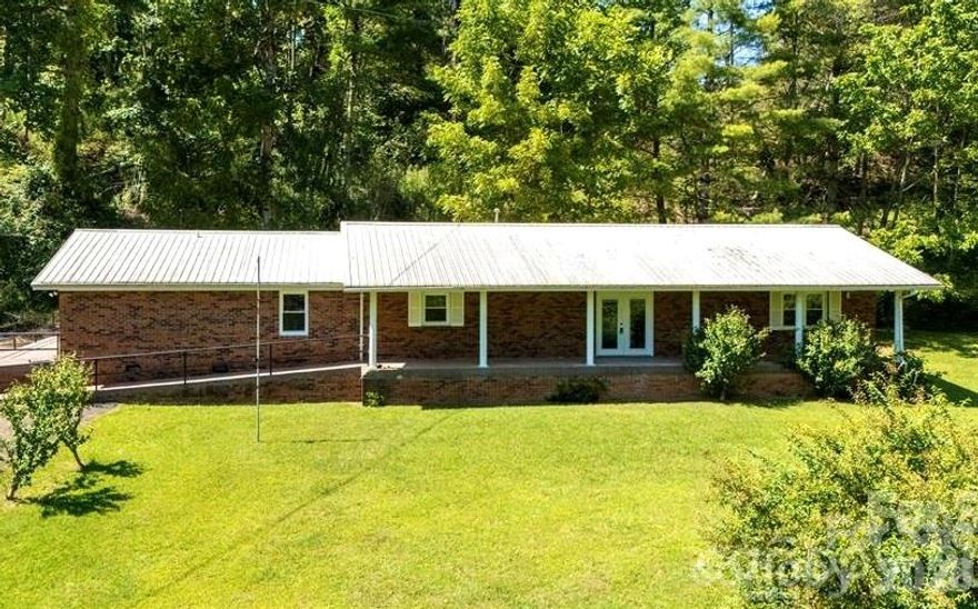 Price Drop! Great time to buy before interest rate go up again; 2,132 sq ft of Mountain Serenity on 1.39 Unrestricted Acres-No "HOA fees". A private mountain sanctuary-impeccably maintained all-brick ranch where rustic charm meets modern luxury on a lush, open lawn framed by a gentle, year-round creek flowing across the front. Wake up to refreshing mountain air and the soothing sounds of nature—your gateway to true Appalachian bliss. Spacious Living Room features shiny refinished Oak Hardwood Floors and a beautiful Native-Stone Fireplace with new gas logs, perfect for cozy evenings. The gourmet Kitchen is a chef’s dream: rich oak cabinetry, brand-new granite countertops, stainless steel appliances, tile floors and a spacious pantry for effortless organization.  New Energy-efficient windows flood the space with natural light; Luxurious updated bathrooms with modern fixtures and durable tile flooring; Sizable laundry, tile floor and outdoor exit. Ceiling fans in key rooms for year-round breeze. Efficient heat pump and durable metal roof for worry-free living; Ceiling fans in key rooms for year-round breeze.  Many detail have been thoughtfully upgraded for comfort and style: 2-expansive primary suites, each with private ensuites—one fully handicap-accessible shower with zero-step entry and grab bars. The standout master suite is exceptionally spacious and offers incredible versatility: its large, open area could easily be converted into a separate living quarters or in-law suite/apartment—complete with room for a living room/kitchen combo, an additional bedroom space, a huge private bathroom and a private entrance for added independence. This thoughtful layout opens up endless possibilities, such as multi-generational living, hosting extended family with privacy or creating a duplex-style setup for potential rental income or guest accommodations. Two additional bedrooms and a third full bath provide further flexibility: guest quarters, home office, craft studio or gym. With single-level living, this home is designed for ease and accessibility at every turn. Outside, the possibilities continues on 1.39 acres of unrestricted land: Two versatile storage buildings for tools, toys or hobbies;  Paved driveway for seamless access; Ample space for gardening, livestock, a custom garage/workshop; Prime location just 4 miles from the renowned Penland School of Craft and minutes to the sparkling Toe River, scenic Blue Ridge Parkway, iconic Appalachian Trail and Pisgah National Forest. Explore hiking, fishing, arts and adventure right from your doorstep. Charming towns like Bakersville, Spruce Pine, and Burnsville are a quick, picturesque drive away. Move-in ready and brimming with potential—whether as a peaceful single-family retreat or enhanced with separate living areas to accommodate more people and lifestyles. Add your personal flair to make it uniquely yours. This isn’t just a home; it’s a lifestyle of freedom, tranquility, endless outdoor inspiration and adaptable space for whatever life brings next. (Rooms with furniture are AI staged). Schedule your private showing today—your mountain paradise awaits!  Seller is anxious for an offer.....