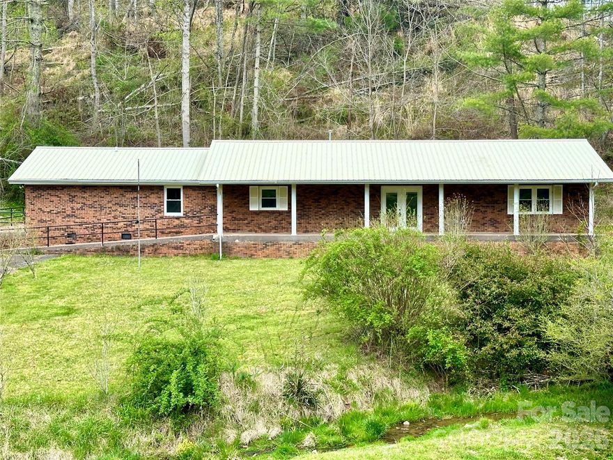 Price Drop! Great time to buy before interest rate go up again; 2,132 sq ft of Mountain Serenity on 1.39 Unrestricted Acres-No "HOA fees". A private mountain sanctuary-impeccably maintained all-brick ranch where rustic charm meets modern luxury on a lush, open lawn framed by a gentle, year-round creek flowing across the front. Wake up to refreshing mountain air and the soothing sounds of nature—your gateway to true Appalachian bliss. Spacious Living Room features shiny refinished Oak Hardwood Floors and a beautiful Native-Stone Fireplace with new gas logs, perfect for cozy evenings. The gourmet Kitchen is a chef’s dream: rich oak cabinetry, brand-new granite countertops, stainless steel appliances, tile floors and a spacious pantry for effortless organization.  New Energy-efficient windows flood the space with natural light; Luxurious updated bathrooms with modern fixtures and durable tile flooring; Sizable laundry, tile floor and outdoor exit. Ceiling fans in key rooms for year-round breeze. Efficient heat pump and durable metal roof for worry-free living; Ceiling fans in key rooms for year-round breeze.  Many detail have been thoughtfully upgraded for comfort and style: 2-expansive primary suites, each with private ensuites—one fully handicap-accessible shower with zero-step entry and grab bars. The standout master suite is exceptionally spacious and offers incredible versatility: its large, open area could easily be converted into a separate living quarters or in-law suite/apartment—complete with room for a living room/kitchen combo, an additional bedroom space, a huge private bathroom and a private entrance for added independence. This thoughtful layout opens up endless possibilities, such as multi-generational living, hosting extended family with privacy or creating a duplex-style setup for potential rental income or guest accommodations. Two additional bedrooms and a third full bath provide further flexibility: guest quarters, home office, craft studio or gym. With single-level living, this home is designed for ease and accessibility at every turn. Outside, the possibilities continues on 1.39 acres of unrestricted land: Two versatile storage buildings for tools, toys or hobbies;  Paved driveway for seamless access; Ample space for gardening, livestock, a custom garage/workshop; Prime location just 4 miles from the renowned Penland School of Craft and minutes to the sparkling Toe River, scenic Blue Ridge Parkway, iconic Appalachian Trail and Pisgah National Forest. Explore hiking, fishing, arts and adventure right from your doorstep. Charming towns like Bakersville, Spruce Pine, and Burnsville are a quick, picturesque drive away. Move-in ready and brimming with potential—whether as a peaceful single-family retreat or enhanced with separate living areas to accommodate more people and lifestyles. Add your personal flair to make it uniquely yours. This isn’t just a home; it’s a lifestyle of freedom, tranquility, endless outdoor inspiration and adaptable space for whatever life brings next. (Rooms with furniture are AI staged). Schedule your private showing today—your mountain paradise awaits!  Seller is anxious for an offer.....