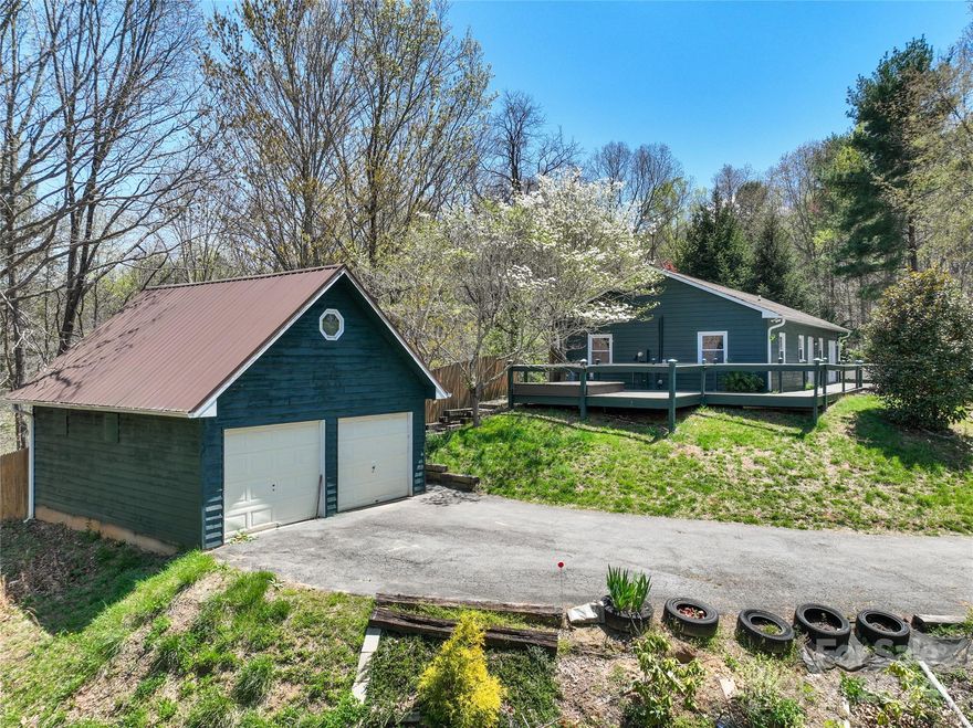 Experience tranquility in this delightful 3-bedroom, 2-bath home gracefully positioned on 1.09 acres of land. Revel in the privacy and security afforded by the fenced backyard. Admire the captivating vistas from the expansive picture window in the living room, complemented by the inviting ambiance of the gas fireplace. The kitchen has beautiful wood features giving the home a cabin-like feel. Host gatherings with ease in the dining room, featuring French doors that seamlessly lead to the generous wrap-around porch. Additionally, the detached garage offers potential for a workshop and boasts a great unfinished upstairs space with endless possibilities. Conveniently located with easy paved access, just 10 minutes to Canton, 15 minutes to Waynesville, and 30 minutes to Asheville.